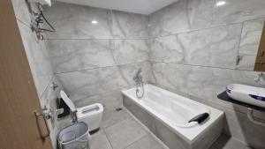 a bathroom with a tub and a toilet and a sink at Hotel Rose Gold in Ahmedabad
