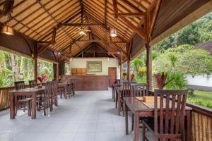an outdoor dining area with wooden tables and chairs at Crystal Bay Villa in Nusa Penida