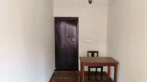 阿勒皮Kuttichira Heritage Home的木门,带桌椅的房间