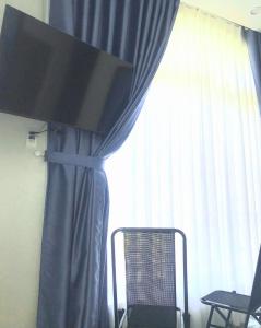 a window with a blue curtain and a chair in front at Moonlight House in Da Thanh