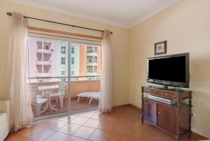 a living room with a television and a balcony at Mar Salgado Beach Apartment in Armação de Pêra
