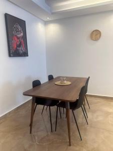 a dining room table with chairs and a clock on a wall at Joli appartement proche de la plage in Agadir +11 photos