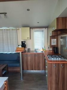 a kitchen with wooden cabinets and a blue couch at Mobil Home climatisé 3 chambres - Parc des 7 fonts in Agde