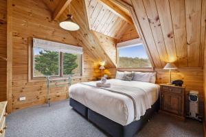 ein Schlafzimmer mit einem großen Bett in einer Holzhütte in der Unterkunft Bimberdong House in Crackenback