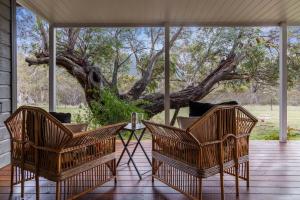 Zwei Stühle und ein Tisch auf einer Veranda mit einem Baum in der Unterkunft Bimberdong House in Crackenback