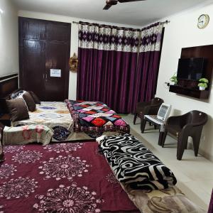 a room with two beds and a couch and a table at Nainital Cotteges in Rāmgarh