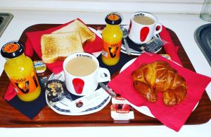 a tray of breakfast food with coffee and croissants and drinks at Hostal Doña María in Valdemoro