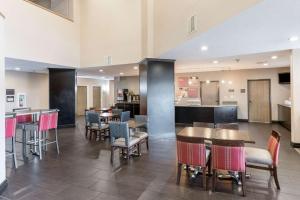 a restaurant with tables and chairs and a kitchen at Comfort Suites Monroe in Monroe
