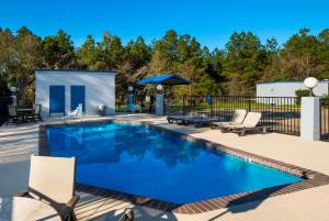 a swimming pool with chairs and an umbrella at Quality Inn near Parc Natchitoches in Natchitoches