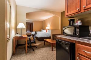 a small hotel room with a bed and a kitchen at Quality Suites New Iberia in New Iberia