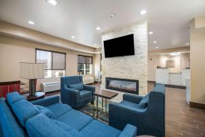 a living room with a blue couch and a fireplace at Comfort Inn Bossier City Casino Area near Shreveport Downtown in Bossier City