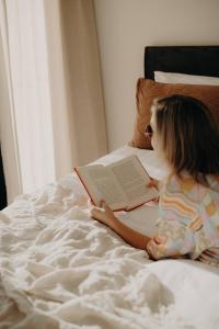 une petite fille assise sur un lit en lisant un livre dans l'établissement Dudley Villa, à Evans Head