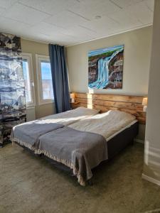 a bed in a bedroom with a painting on the wall at Kuttainen Lodge in Karesuando