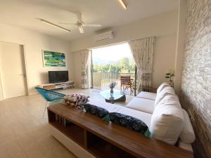 a living room with a couch and a large window at By The Sea Suite,Batu Ferringhi in Batu Ferringhi