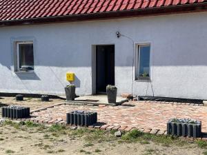 a white house with a brick patio and a door at Wiejskie Kwatery Dolina Baryczy in Ujeździec Mały