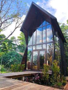 a glass house with a large window on a deck at Cheewatra Farmstay Phuket ชีวาตรา ฟาร์มสเตย์ ภูเก็ต in Thalang
