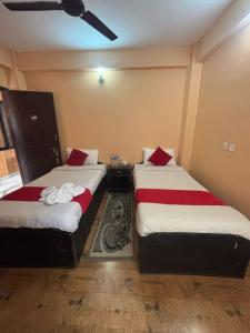 a bedroom with two beds with red and white sheets at Hotel Fewa Lake View in Pokhara