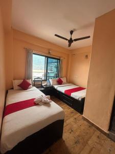 two beds in a room with a window at Hotel Fewa Lake View in Pokhara