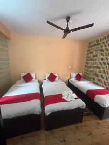 a room with three beds with red and white sheets at Hotel Fewa Lake View in Pokhara