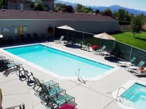 a large swimming pool with chairs and umbrellas at Broadway Inn Conference Center in Missoula