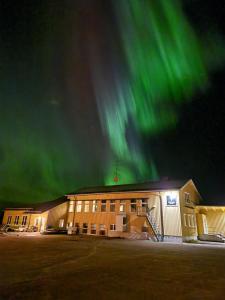 a building with the green northern lights in the sky at Kuttainen Lodge in Karesuando