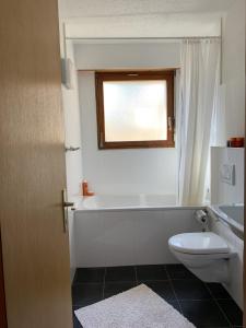 a bathroom with a tub and a toilet and a window at Bel Air C27 in Champéry