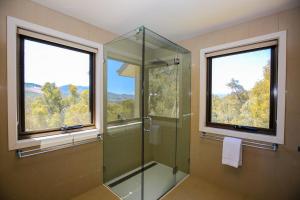 a bathroom with a glass shower and two windows at Kangaroo Lodge in Bright +29 photos