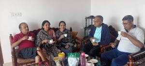 a group of people sitting on a couch drinking coffee at Udita Homestay Prayas in Shānti Niketan