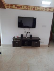 a living room with a flat screen tv on a wall at Udita Homestay Prayas in Shānti Niketan