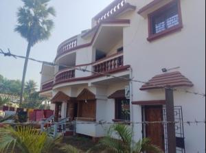 a white house with a palm tree in front of it at Udita Homestay Prayas in Shānti Niketan