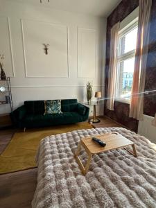 ein Wohnzimmer mit einem grünen Sofa und einem Couchtisch in der Unterkunft Premium-Apartment im Duisburger Süden, nähe Düsseldorf Flughafen & Messe, Komplett ausgestattetes Apartment mit modernen Altbau-Flair in Duisburg