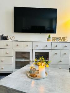 a living room with a tv and a table with flowers at charmante Ferienwohnung am Stadtwald von Plauen in Plauen +3 photos