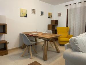 ein Esszimmer mit einem Holztisch und einem gelben Stuhl in der Unterkunft Apartamento tranquilo en la Villa de Teguise Lanzarote in Teguise