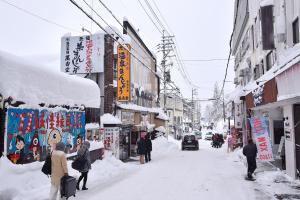 a snow covered street with people walking down the street at Matsuya hotel in Myoko