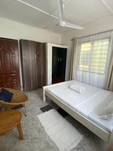 een slaapkamer met een bed, een stoel en een raam bij Serenity Eusy Diani in Ukunda