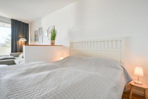 una camera da letto bianca con un letto e un divano di Ferienwohnung Hygge Sol Mare Whg 52 mit Schwimmbad Innenpool und Sauna Kellenhusen a Kellenhusen