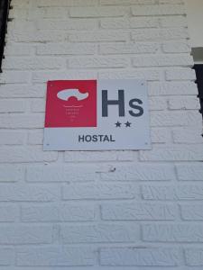 a sign hanging on a white brick wall at Hostal LA SIERRA in Herreruela de Oropesa