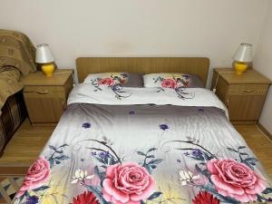 a bed with pink flowers on it in a bedroom at Garsonieră Brazda lui Novac in Craiova
