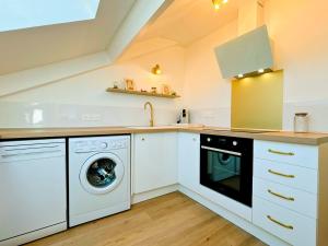 a kitchen with a washing machine and a sink at Sous les toits de la Digue in Verdun-sur-Meuse