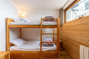 two bunk beds in a small room with a window at Appartement Aime 2000 in Mâcot La Plagne