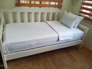 a white bed with white sheets and pillows on it at Family-Friendly Cabin Hideaway, Alfonso Tagaytay in Alfonso