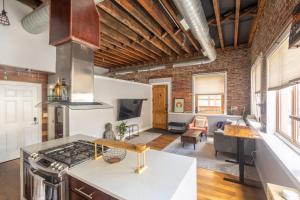 a kitchen with a stove top oven next to a living room at Stylish SOHO-Inspired Loft, 15 Min to NYC Times Square in Union City