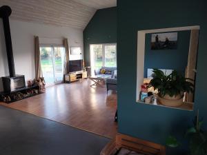 a living room with blue walls and a wooden floor at Maison très agréable in Pleyber-Christ