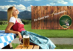 a woman sitting on a bench with a glass of beer at Beim Krahwirt in Deggendorf