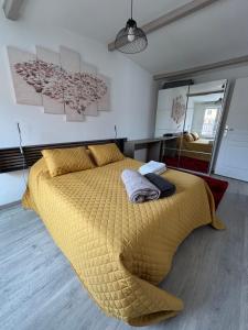 a bedroom with a large bed with a yellow comforter at L Olivier in Nanterre