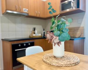 a vase with flowers on a table in a kitchen at A city oasis - full apartment with balcony in Perth