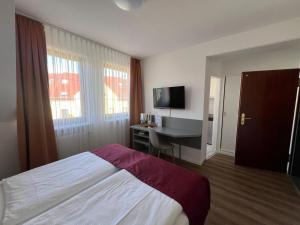 a bedroom with a bed and a desk and a television at Pension am Markt in Lübben