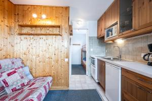 a kitchen with wooden cabinets and a couch in a room at Les Bouquetins A in La Rosière +12 photos