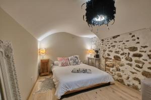 a bedroom with a bed and a stone wall at L'atypique Chez Les Amoureux in Le Touvet