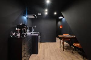 a black room with a table and a kitchen at L'atypique Chez Les Amoureux in Le Touvet
